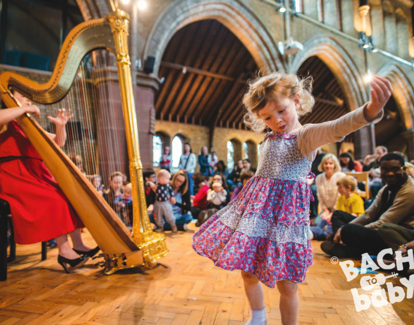 child dancing to harpist at bach to baby concert 