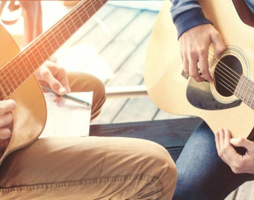 student and teacher holding guitars
