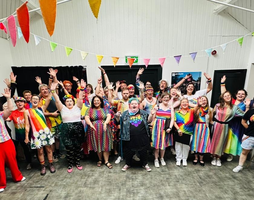 The chorus celebrates in rainbow outfits 